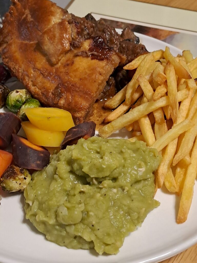 Beef and Guinness pie with mushy peas, chips, and vegetables