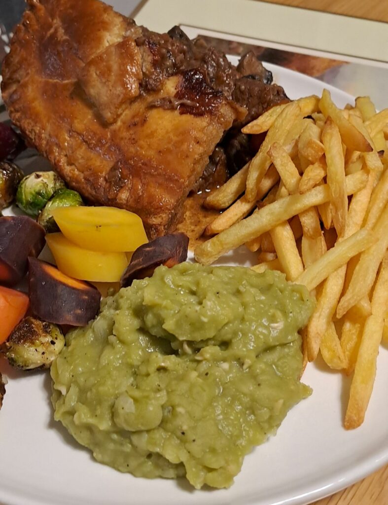 Beef and Guinness pie with mushy peas, chips, and vegetables